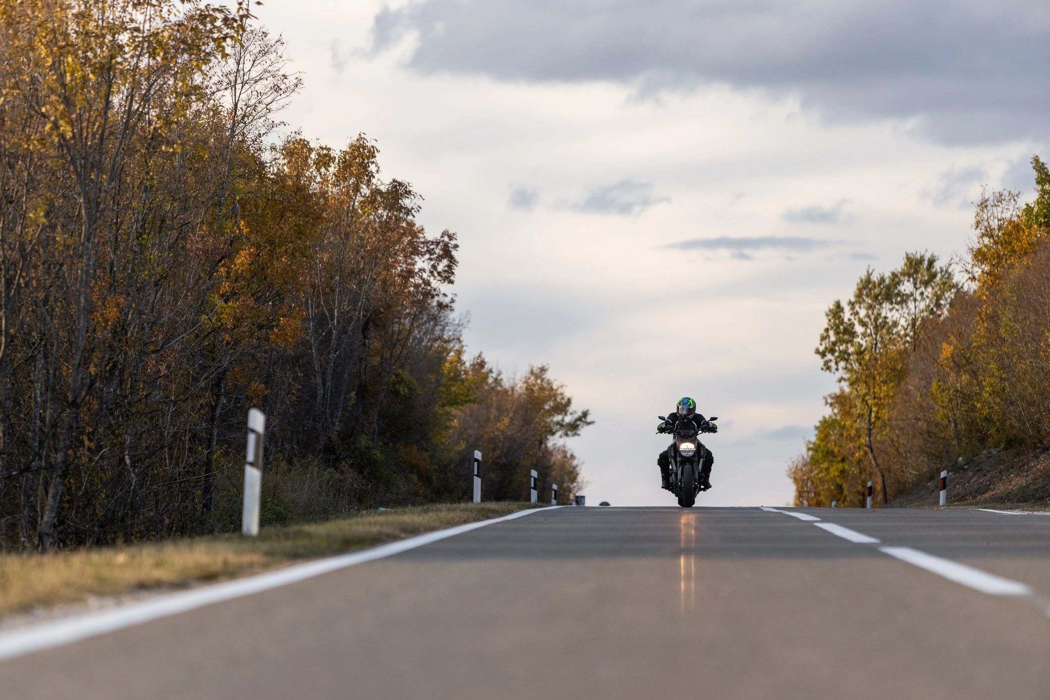 Motorcycle rider traveling along a colorful autumn highway